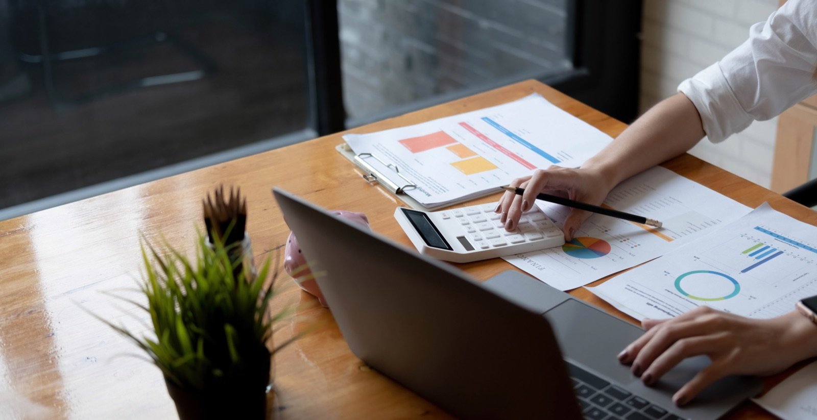 Business professional using a calculator and laptop while reviewing financial documents